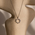 The Pave Sun Necklace in Silver, featuring sparkling pave accents, is displayed on a beige textured mannequin bust.