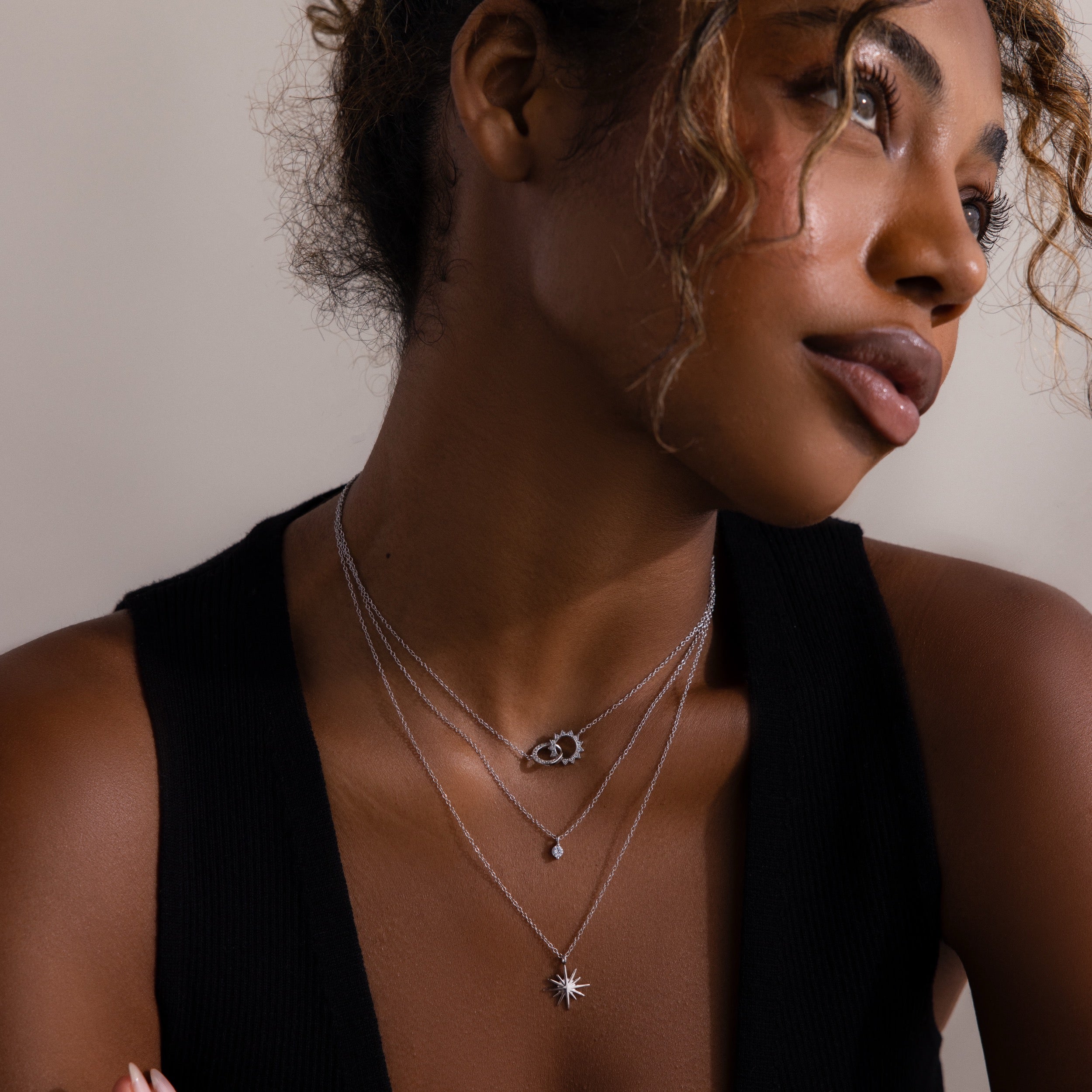 Woman wearing the Laura Starburst Duo Necklace in Silver with a black sleeveless top, looking off to the side.