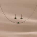 Jade Bar Jewelry Set in Sterling Silver, featuring a silver necklace with a small green bead and matching jade earrings, displayed on a beige background.