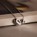 The Duo Pebble Necklace in Silver features two abstract silver pendants on a fine chain—an elegant piece to add artistic charm to your jewelry collection.