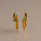 Floating Peridot Huggies—gold hoop earrings with green gemstones, personalized jewelry showcased upright on a neutral background.
