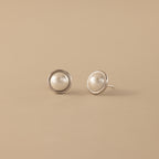 Pearl Bezel Studs in Sterling Silver displayed on a beige background.