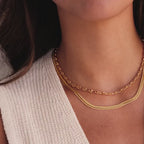 Model showcasing layered gold necklaces, including a mariner chain necklace and a thin mesh chain.