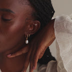 Model showcasing the gold twisted pearl hoop earrings, stacked with a gold hoop earring and pearl cluster drop stud earring.