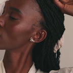 Model wearing gold pavé bow stud earrings paired with a dainty pearl and diamond stud earring.