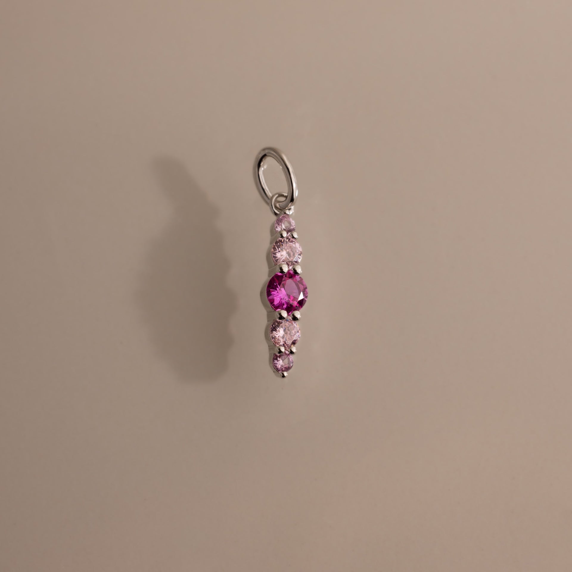 The Ombre Lace Pink Tourmaline Charm features a silver pendant with vertically arranged pink and clear gemstones, making it a perfect personalized charm or thoughtful birth month gift.