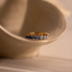 Gold ring with blue ombre gemstones on a beige ceramic dish