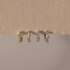 Two pairs of Marquise Cluster Hoop Earrings in gold and silver with clustered CZ diamond stones, displayed on a neutral surface.
