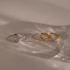Four minimalist rings from the Curve Stacking Set, two in silver and two in gold, arranged on a neutral surface with soft shadows—ideal for a chic stacked look.