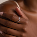 Close-up of a hand wearing the Curve Stacking Set—a silver chevron ring with thin bands—on the middle finger, gently touching the shoulder in a chic stack.