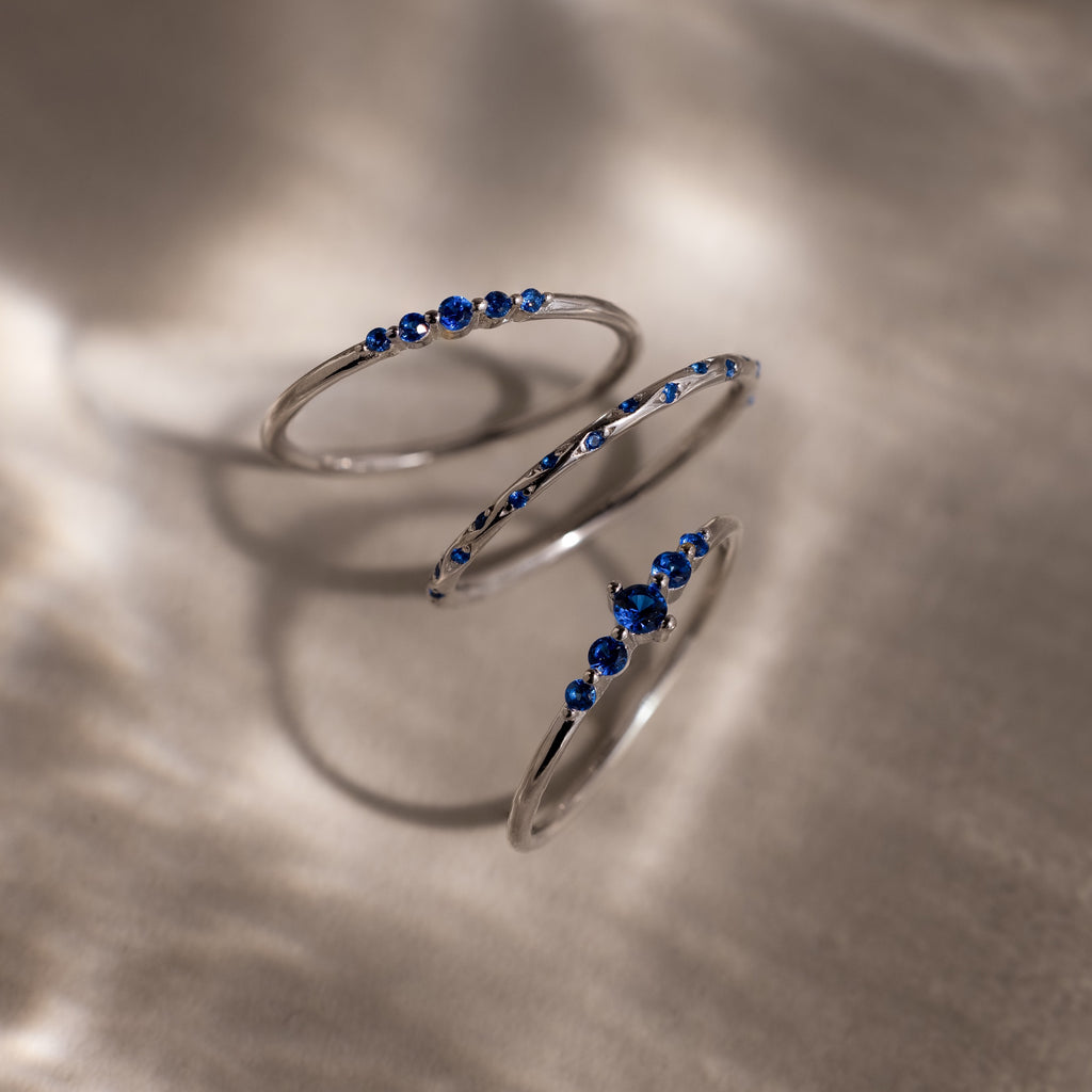 Silver rings with blue gemstones on a textured surface