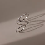 The Crystal Stacking Ring Set in Silver rests on a beige surface, each ring casting soft shadows as their gemstones sparkle delicately.