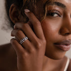 Elegant woman with curly hair showcases the Crystal Stacking Ring Set in Silver, adorned with sparkling gemstones, as she gazes softly at the camera.