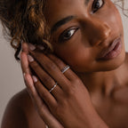 Woman with curly hair gazes softly, her hands near her face showcasing the elegant Crystal Stacking Ring Set in Silver adorned with crystal gemstones.
