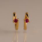 Floating Ruby Huggies: open gold hoop earrings with a single pink gemstone at the center—a modern, personalized twist on classic birthstone jewelry.