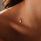The Opal Sea Turtle Charm in 18K Gold, inspired by the seaside, rests gracefully on a person’s collarbone near their neck and shoulder.