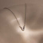 A Dainty Bubble Letter Necklace in Sterling Silver rests on smooth, light-colored skin under soft lighting.