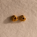 The Rope Knot Studs rest elegantly on a textured beige surface, showcasing timeless style and subtle sophistication.