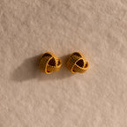 The Rope Knot Studs rest elegantly on a textured beige surface, showcasing timeless style and subtle sophistication.