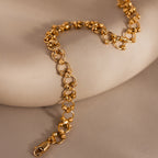 The Orbit Chain Bracelet in 18K Gold features textured circular links and a secure clasp, displayed on a smooth beige surface—an elegant addition to any jewelry collection.