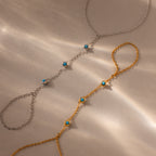 Two Turquoise Hand Chain Bracelets, one in silver and one in gold, each accented with turquoise stones, are displayed on a beige surface—the perfect set for fans of the Turquoise Hand Chain Bracelet.