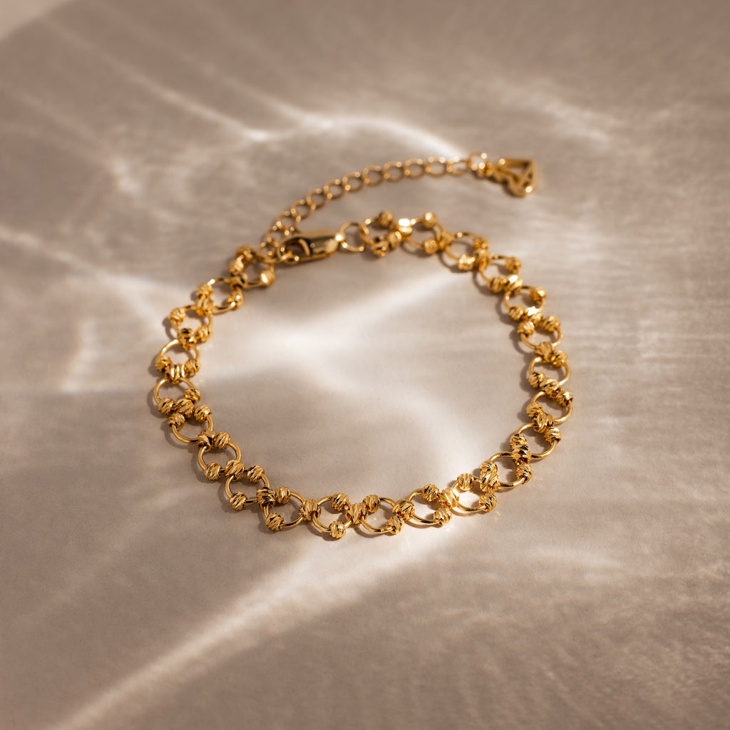 Orbit Chain Bracelet in 18K Gold with textured links on a neutral background, softly lit—an elegant accessory for any occasion.