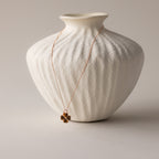 Tiger's Eye Clover Necklace draped over a textured white ceramic vase on a neutral background, perfect as a lucky pendant for any occasion.
