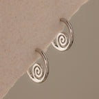Spiral Swirl Hoops in Silver displayed on a textured off-white background—these beachy earrings are the perfect boho vacation jewelry accessory.