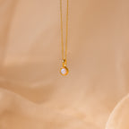 Signet Birthstone Charm in Opal / October, displayed on soft beige fabric—a refined piece that highlights the captivating beauty of opal gemstone charms and the appeal of personalized jewelry.
