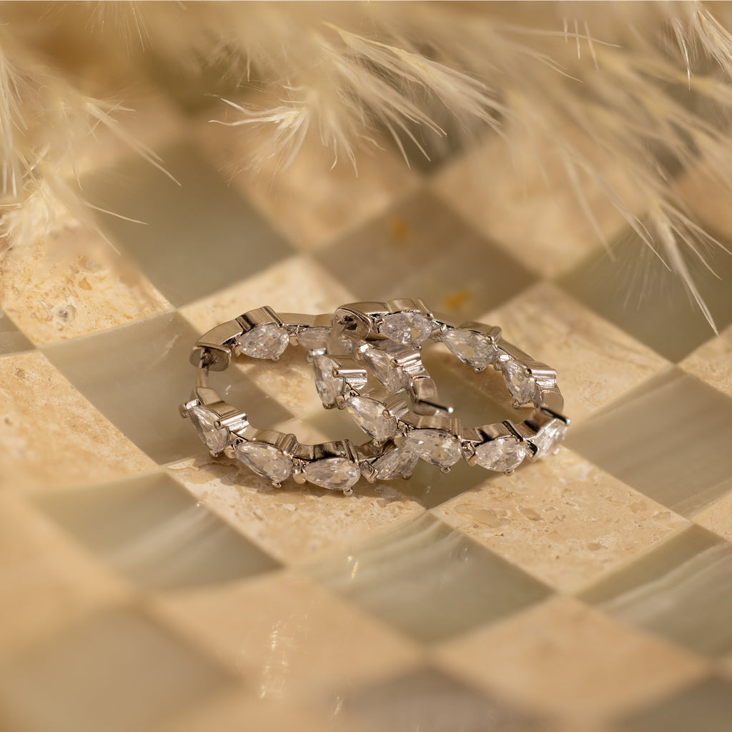 Inside Out Pear Diamond Hoops in Silver, ideal as a bridesmaid gift, showcased on a checkered beige and cream textured background.