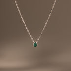 The Multiple Teardrop Birthstone Necklace in Sterling Silver features a delicate chain with small green pendants, displayed on a plain beige background—an elegant keepsake jewellery piece ideal for everyday wear.