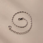 The Oval Beaded Bracelet features silver oval links and polished beads with a lobster clasp, displayed on a beige surface—ideal for fans of modern classic jewelry.