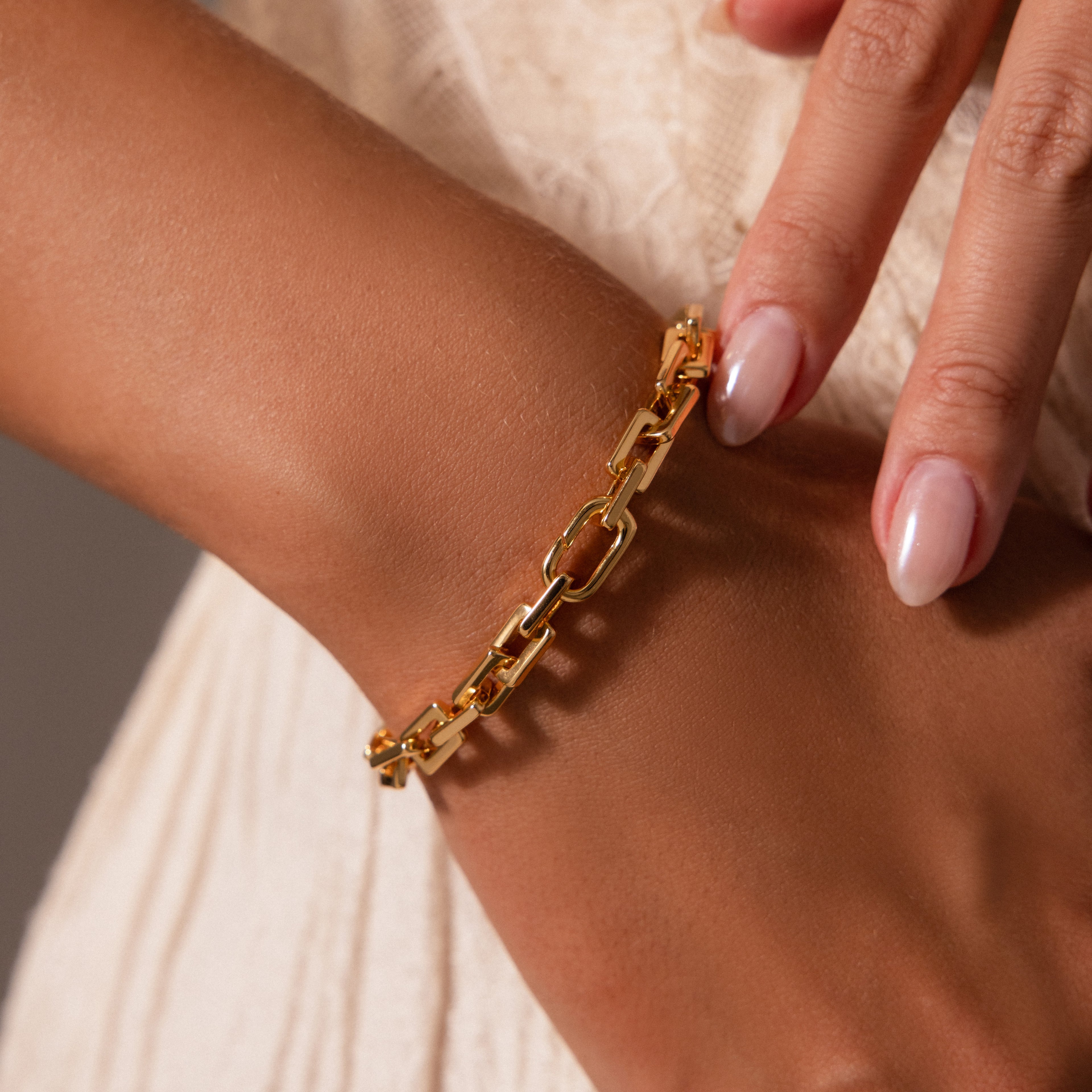 A hand wearing the Eternal Link Bracelet with a geometric design, paired with polished nails and light clothing—ideal for adding a modern touch to your essentials.