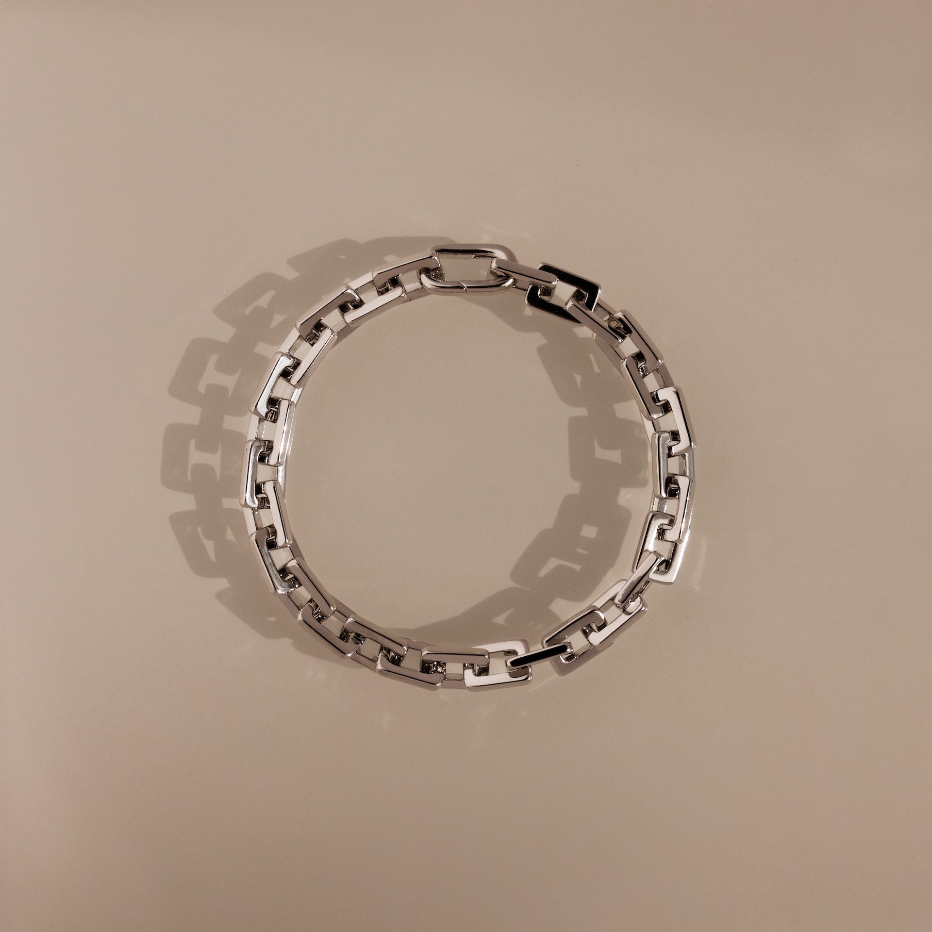 The Eternal Link Bracelet in Silver features rectangular links in a circle on a beige background, highlighting its geometric, modern design.