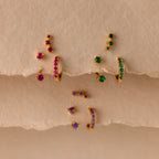 The Blue Zircon Earring Trio Set is elegantly displayed on three beige textured shelves, making it a perfect gift for a birthstone earring set.