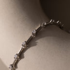 Sprinkle Diamond Tennis Bracelet in Silver displayed on a smooth, light beige surface in soft lighting.
