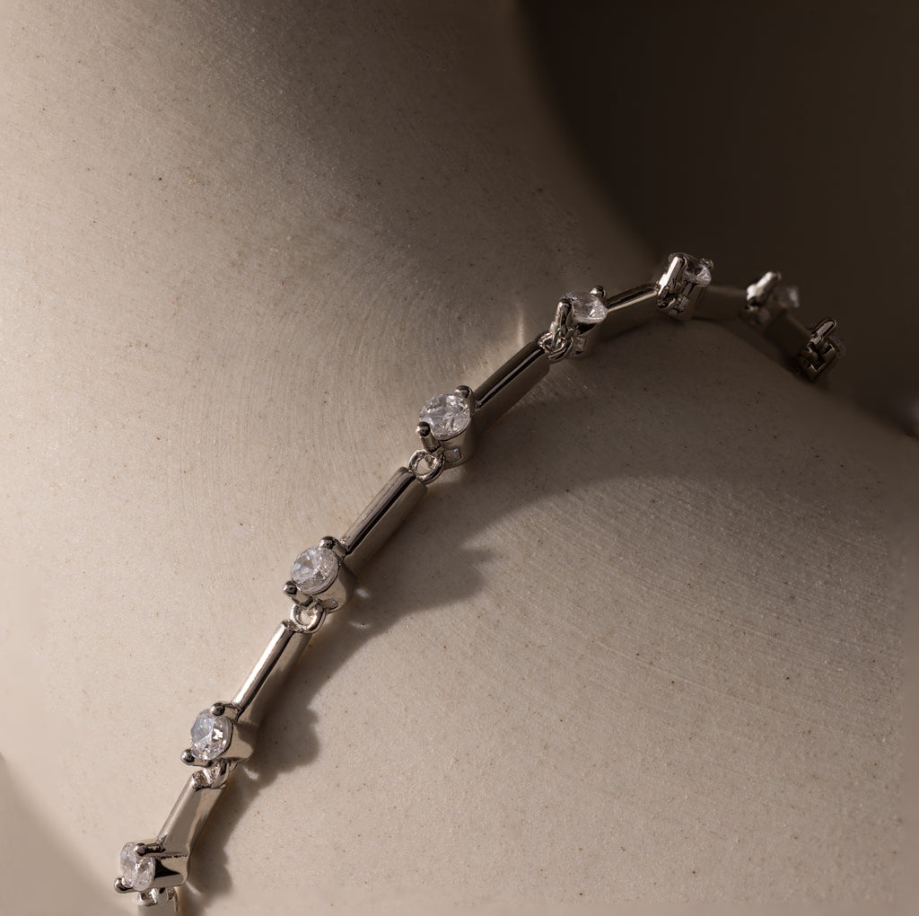 Close-up of the Sprinkle Diamond Tennis Bracelet, featuring delicate round diamonds and elegantly showcased on a smooth, light surface.