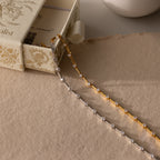 Two delicate chain necklaces, one gold and one silver with small gemstones, displayed on a textured surface—perfect for pairing with the Sprinkle Diamond Tennis Bracelet.