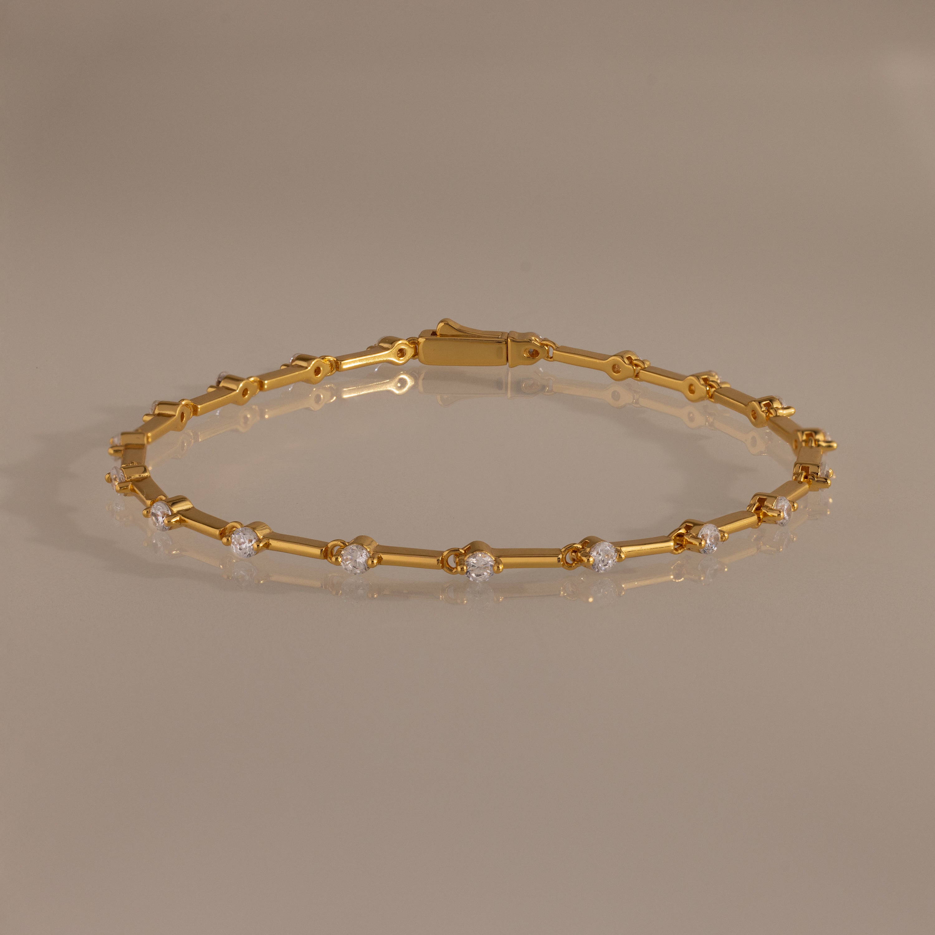 The Sprinkle Diamond Tennis Bracelet in 18K Gold features evenly spaced round diamonds, elegantly displayed on a neutral reflective surface.