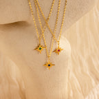 Three Star Birthstone Necklaces featuring colored gemstones are displayed on a textured cream surface—an ideal piece of celestial jewelry and a perfect personalized gift.