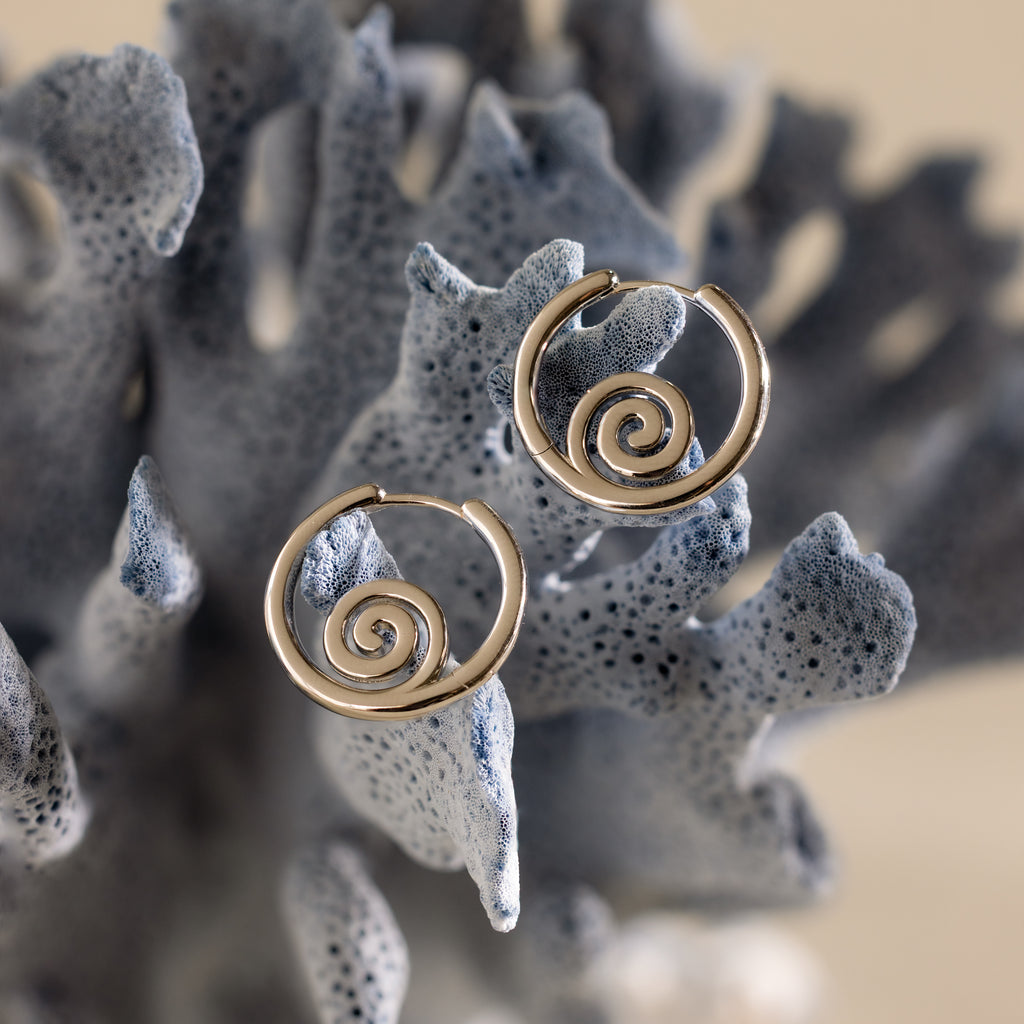 Spiral Swirl Hoops in Silver displayed on a textured, blue-gray coral-like surface—perfect beachy earrings for your next boho vacation jewelry look.