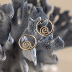Spiral Swirl Hoops in Silver displayed on a textured, blue-gray coral-like surface—perfect beachy earrings for your next boho vacation jewelry look.