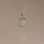The Square Mother of Pearl Necklace in Silver features a shimmering iridescent pendant with a small round stone—ideal for layering on any plain background.