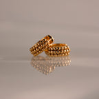 The Beaded Chunky Hoops in 18K Gold, featuring beaded detailing, are displayed on a reflective surface against a soft, neutral background.