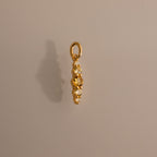 Ombre Lace Topaz Charm: a gold pendant featuring four white gemstones set vertically, displayed on a plain light brown background—an elegant birthstone accessory.