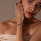 A woman wearing a strapless top and the Organic Mariner Chain Bracelet touches her face in soft lighting, creating a perfect showcase for this contemporary jewelry piece.
