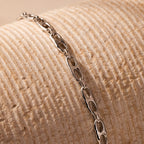 Displayed on a textured cream surface, the Organic Mariner Chain Bracelet in silver features sculptural oval links—an ideal pick for fans of modern, contemporary jewelry.