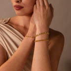 A woman in a beige top wears two gold bracelets on her wrist, including the Diamond Elephant Link Bracelet, with soft lighting and a neutral background.