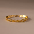 The Diamond Elephant Link Bracelet features a gold design with repeating heart patterns and small diamonds, elegantly displayed on a neutral surface.