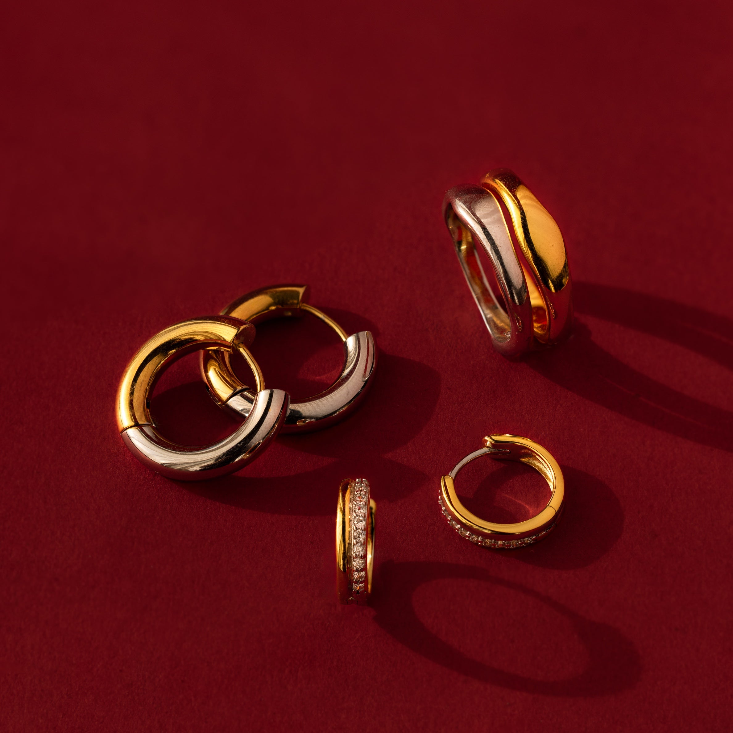 The Duo Form Ring Set is displayed on a red background with dramatic shadows, highlighting its timeless gold and silver design.